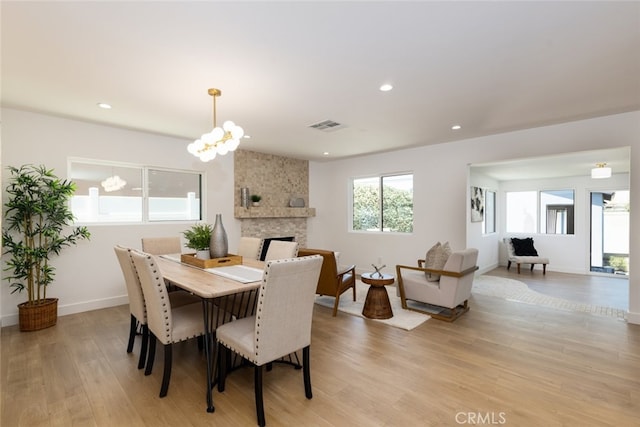 dining space featuring a large fireplace, visible vents, light wood finished floors, and recessed lighting