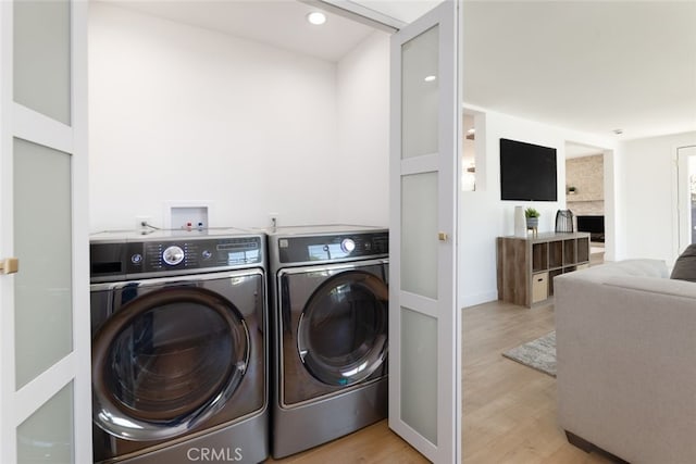 laundry room with laundry area, washing machine and dryer, and light wood finished floors