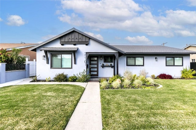 view of front of house featuring fence, a front lawn, board and batten siding, and stucco siding