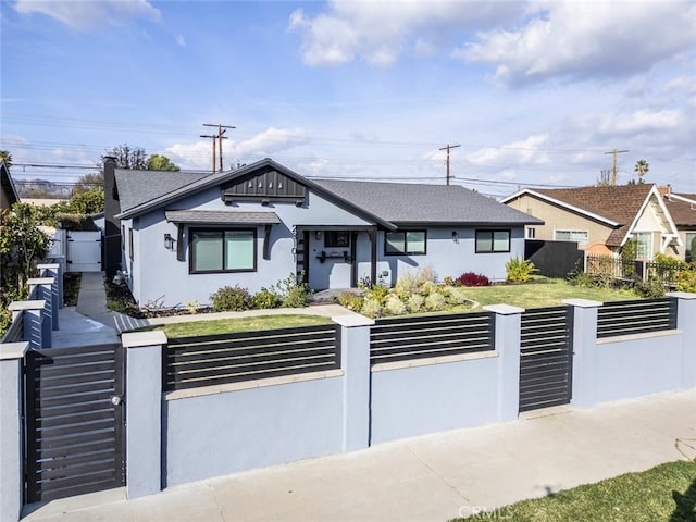 bungalow-style home with a fenced front yard, a gate, and stucco siding