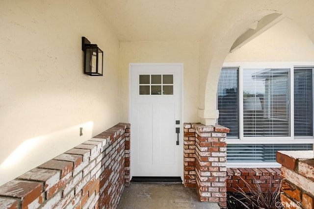 entrance to property featuring brick siding and stucco siding