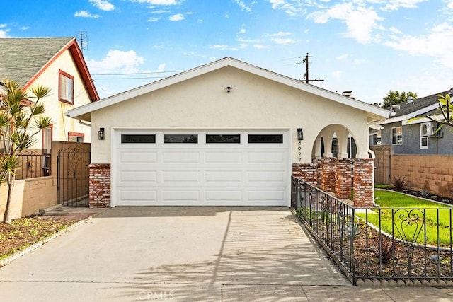 view of front of home with a garage, fence, concrete driveway, and stucco siding