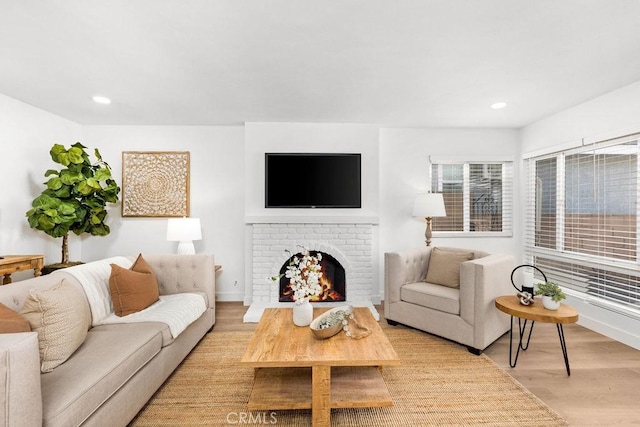 living area featuring light wood-style floors, a fireplace, baseboards, and recessed lighting