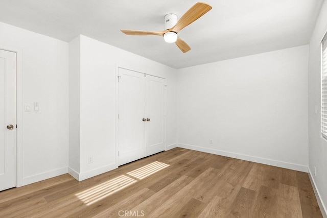 unfurnished bedroom with light wood-type flooring, a closet, baseboards, and a ceiling fan