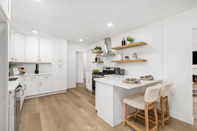 kitchen with stainless steel appliances, ventilation hood, light countertops, white cabinetry, and open shelves