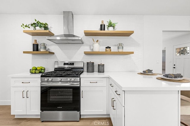 kitchen featuring ventilation hood, light countertops, stainless steel range with gas cooktop, white cabinetry, and open shelves