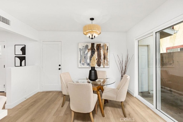 dining space featuring light wood-style flooring, visible vents, and baseboards