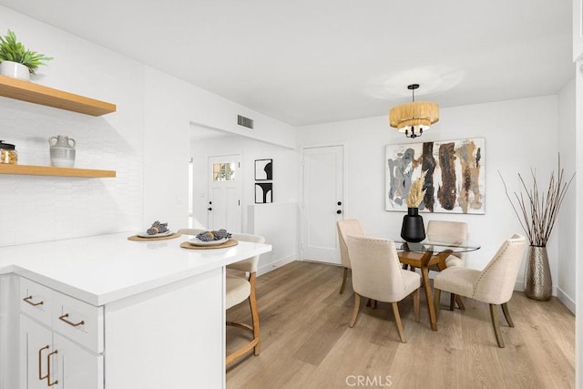 dining space featuring light wood-type flooring, visible vents, and baseboards