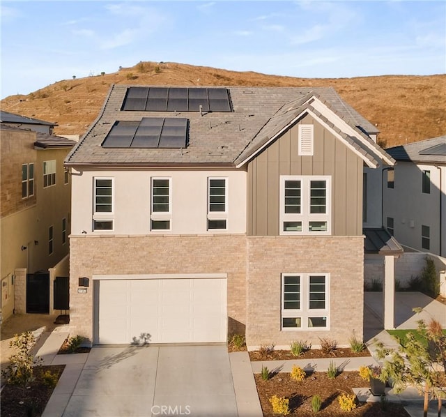 view of front of property with a mountain view, a garage, and solar panels