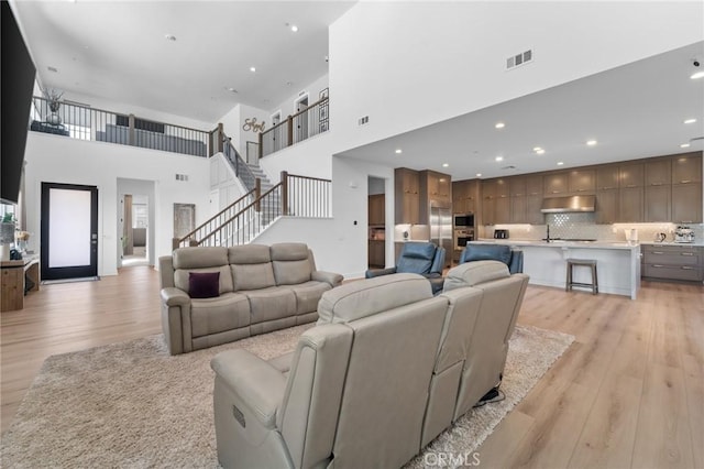 living room with a high ceiling and light hardwood / wood-style flooring