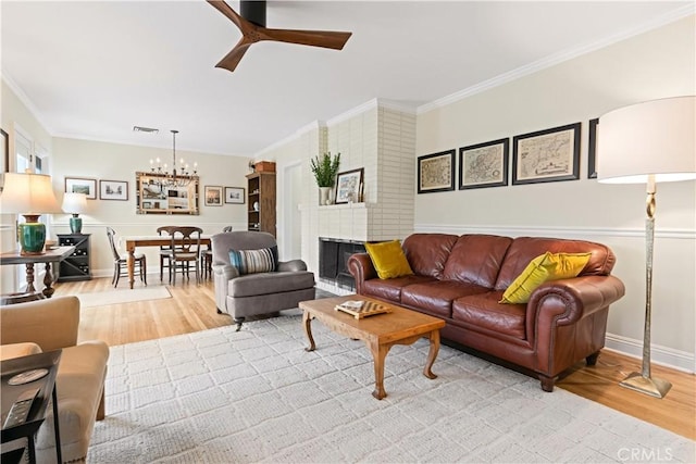 living room with ornamental molding, hardwood / wood-style floors, and ceiling fan with notable chandelier