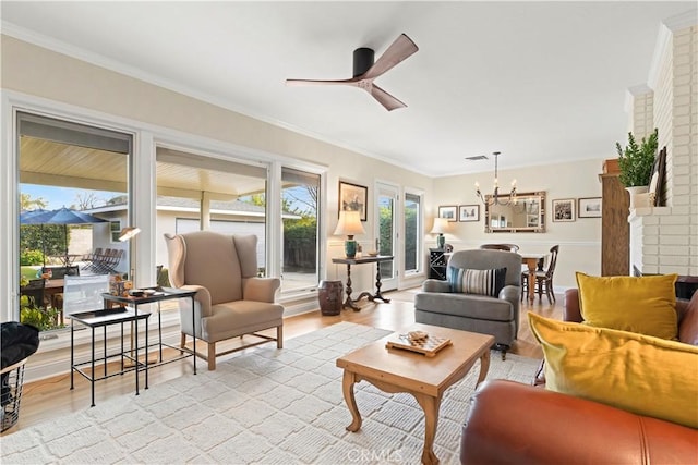 living room with ceiling fan with notable chandelier, light hardwood / wood-style flooring, and crown molding