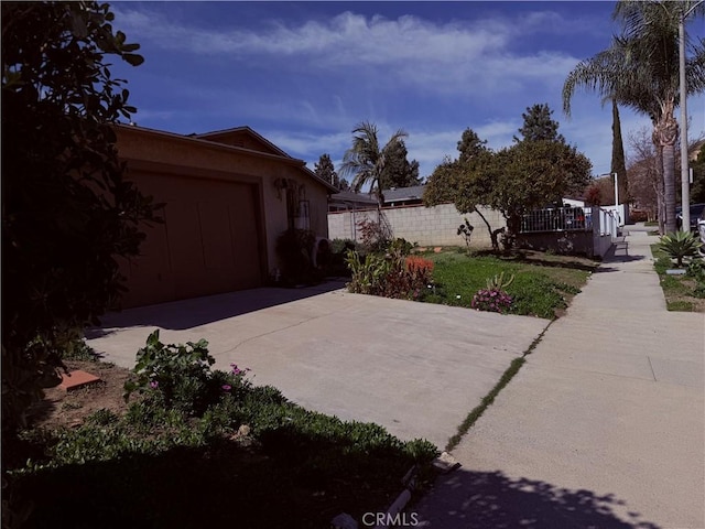 view of patio / terrace with a garage, concrete driveway, and fence