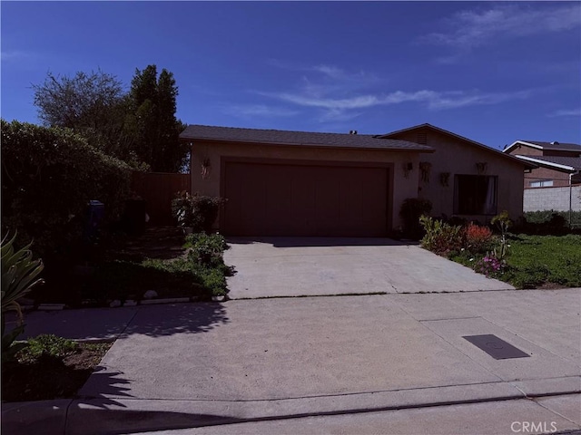 view of front of home with concrete driveway, fence, an attached garage, and stucco siding