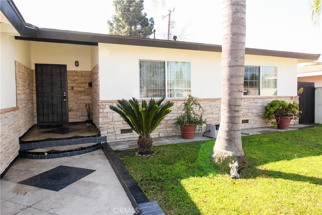 property entrance featuring stone siding, a lawn, and stucco siding