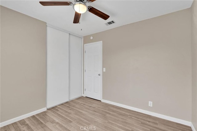 spare room with a ceiling fan, light wood-type flooring, visible vents, and baseboards