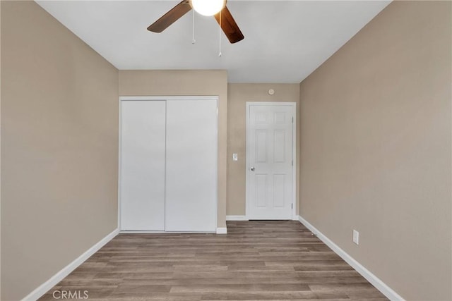 unfurnished bedroom featuring light wood-type flooring, a ceiling fan, baseboards, and a closet