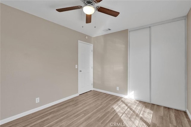 spare room featuring light wood finished floors, visible vents, baseboards, and ceiling fan