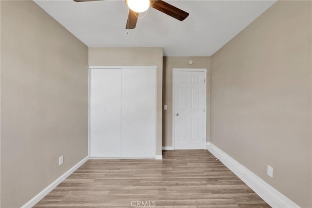 unfurnished bedroom featuring light wood-type flooring, a closet, ceiling fan, and baseboards