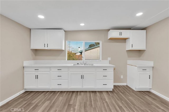 kitchen featuring white cabinets, light countertops, and a sink