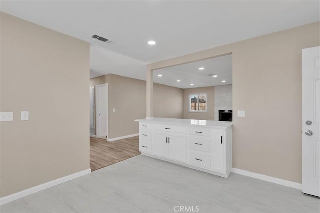 kitchen with recessed lighting, light countertops, open floor plan, white cabinetry, and baseboards