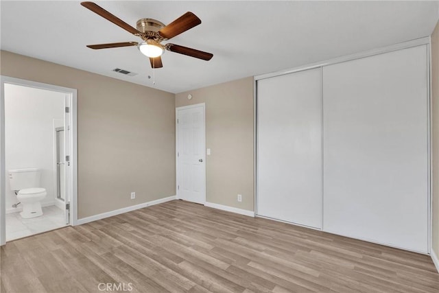 unfurnished bedroom with a closet, visible vents, connected bathroom, and light wood-style flooring