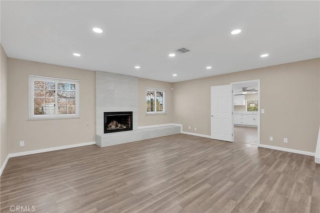 unfurnished living room featuring light wood finished floors, a fireplace, recessed lighting, and baseboards