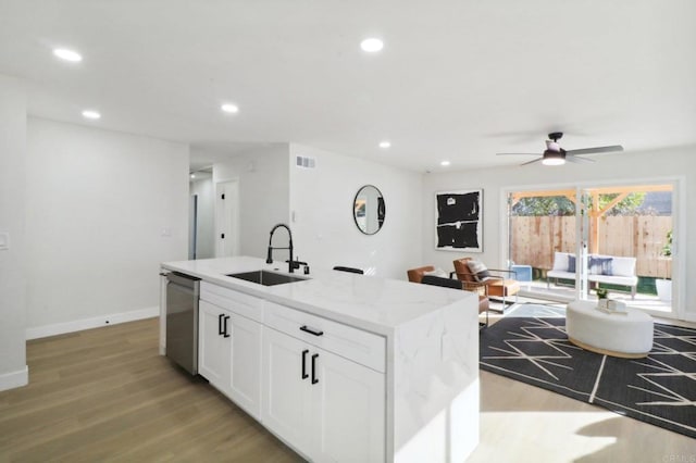 kitchen with a center island with sink, sink, light stone counters, dishwasher, and white cabinets