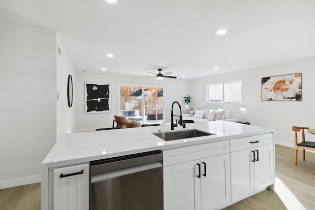 kitchen with white cabinetry, light hardwood / wood-style flooring, light stone countertops, sink, and stainless steel dishwasher