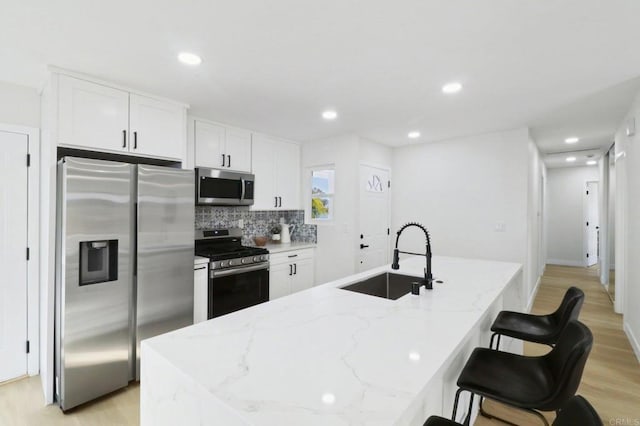 kitchen with sink, stainless steel appliances, white cabinets, and light stone counters