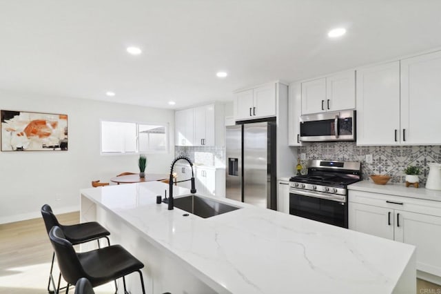 kitchen with white cabinetry, appliances with stainless steel finishes, sink, and a breakfast bar