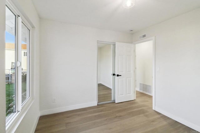 unfurnished bedroom featuring multiple windows, a closet, and light hardwood / wood-style floors