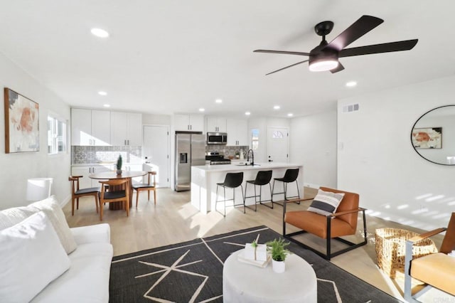 living room featuring sink, ceiling fan, and light hardwood / wood-style floors