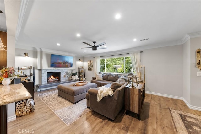 living room featuring light wood-type flooring, ornamental molding, and ceiling fan