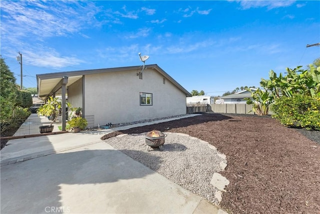 view of property exterior with a patio and a fire pit