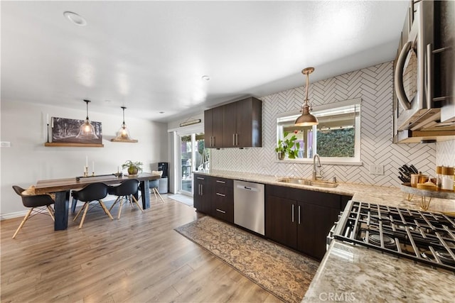 kitchen featuring decorative light fixtures, sink, stainless steel appliances, and dark brown cabinetry