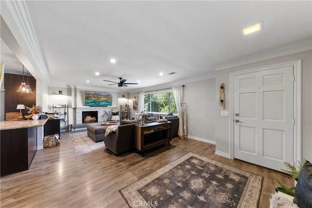 living room with ornamental molding, ceiling fan, and light hardwood / wood-style flooring