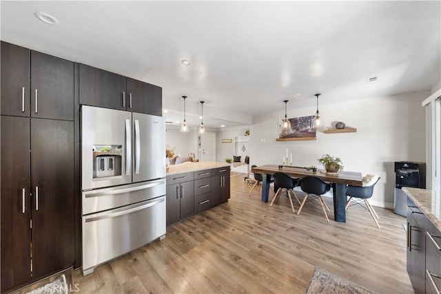 kitchen with decorative light fixtures, light hardwood / wood-style floors, dark brown cabinetry, and stainless steel fridge