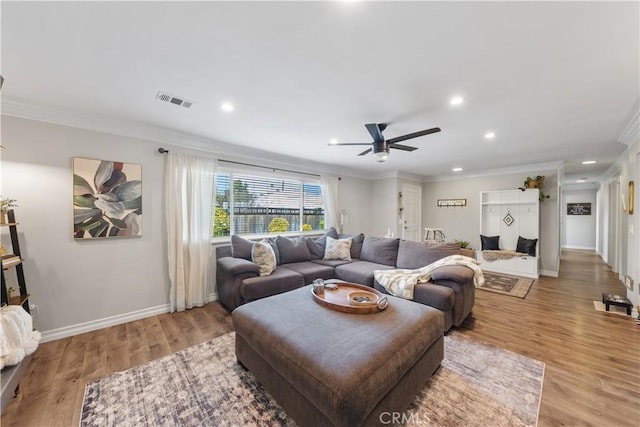 living room featuring ceiling fan, ornamental molding, and light hardwood / wood-style flooring