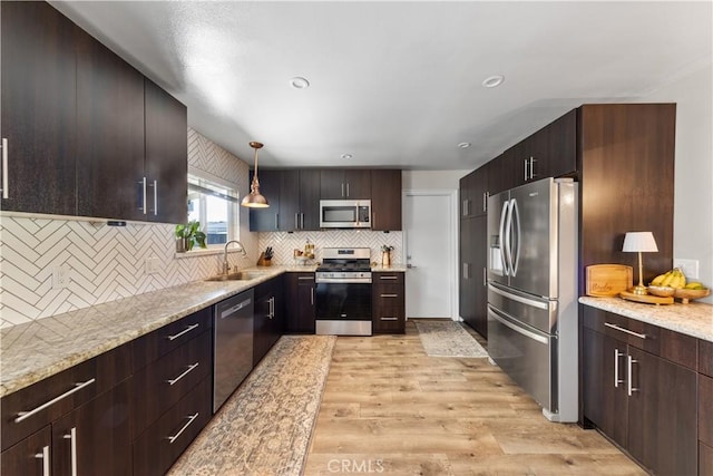 kitchen with light hardwood / wood-style flooring, hanging light fixtures, stainless steel appliances, decorative backsplash, and sink