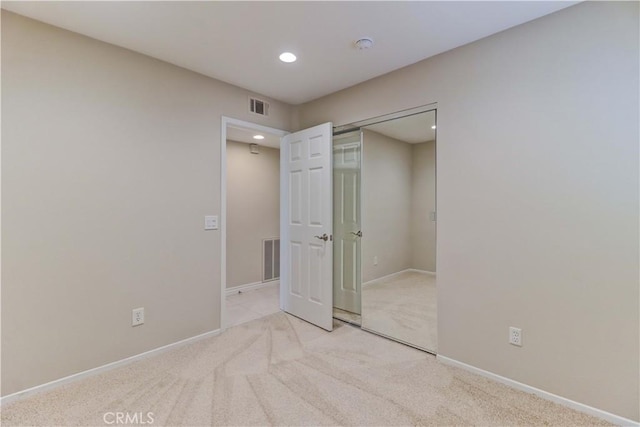 unfurnished bedroom with light carpet, a closet, visible vents, and baseboards