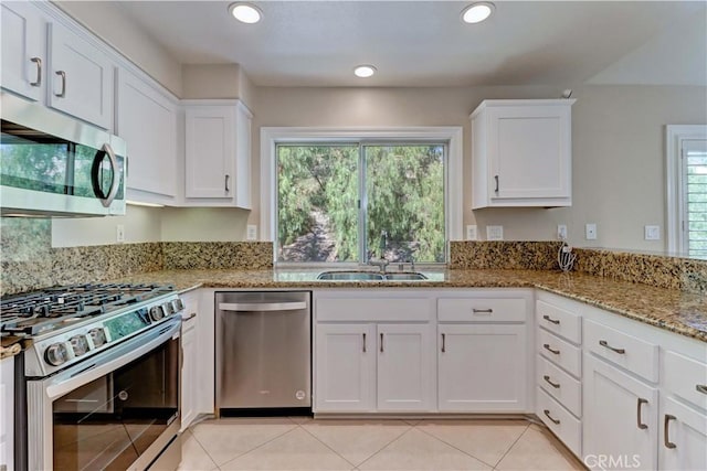 kitchen with light stone counters, recessed lighting, appliances with stainless steel finishes, white cabinetry, and a sink