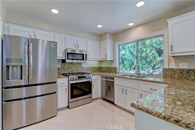 kitchen featuring light stone counters, appliances with stainless steel finishes, white cabinets, and a sink