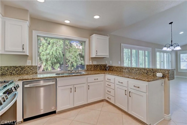 kitchen with white cabinets, light stone counters, appliances with stainless steel finishes, a peninsula, and a sink