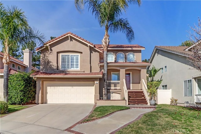 mediterranean / spanish house featuring a garage, stucco siding, stairs, a tiled roof, and concrete driveway