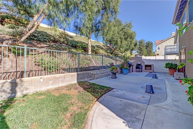 view of yard with a patio, an outdoor fireplace, and a fenced backyard