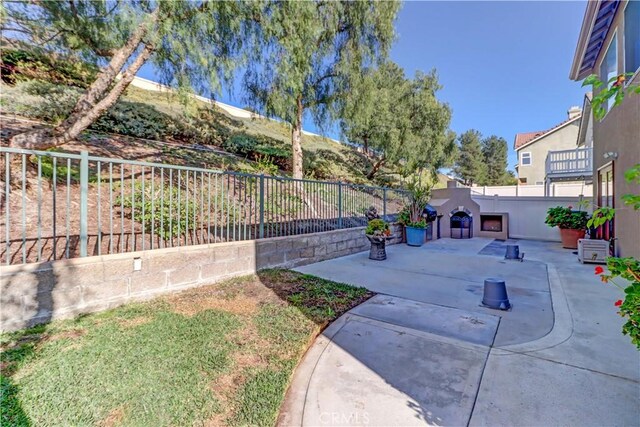 view of yard featuring a fenced backyard, a patio, and exterior fireplace