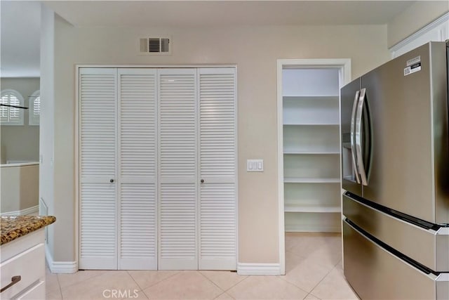 kitchen with light tile patterned flooring, visible vents, white cabinets, stainless steel fridge with ice dispenser, and light stone countertops