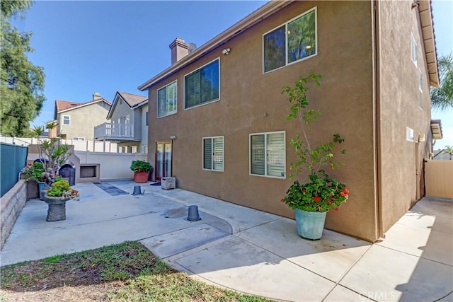 rear view of property with a patio area, a fenced backyard, a chimney, and stucco siding