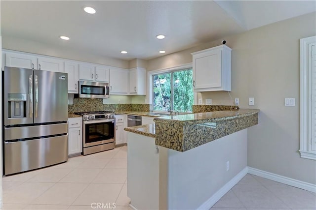 kitchen featuring white cabinets, a sink, stainless steel appliances, a peninsula, and light tile patterned floors